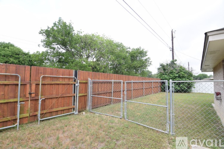 A chain link fence separates a grassy area from a building.