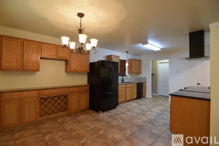 A kitchen with wooden cabinets and a black refrigerator.