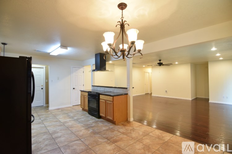 A kitchen with a black refrigerator and a chandelier hanging from the ceiling.