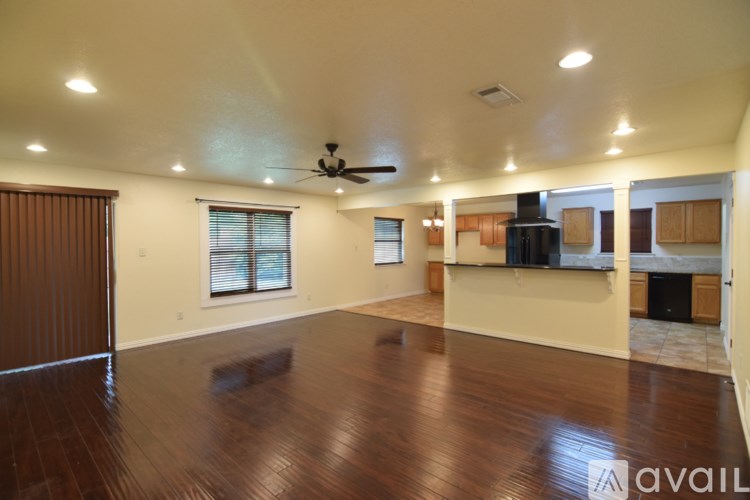 A spacious room with wooden floors and a ceiling fan.
