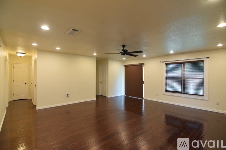 A spacious room with wooden floors and a ceiling fan.