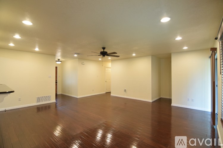 A spacious room with wooden floors and a ceiling fan.