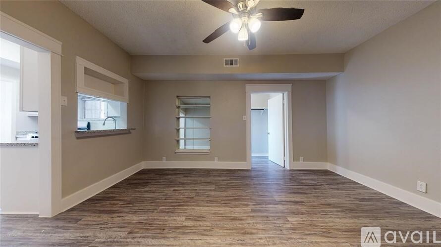 A spacious room with a ceiling fan and wooden flooring.
