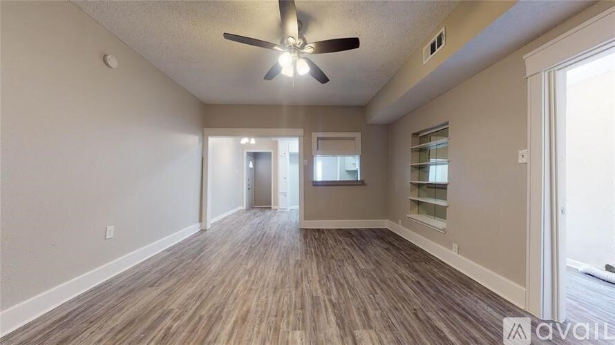 A spacious room with wood flooring and a ceiling fan.