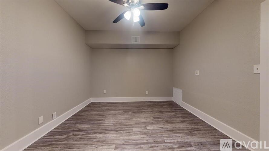 A room with a ceiling fan and wooden flooring.