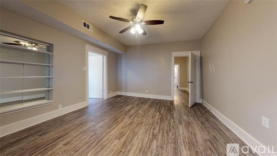 A room with a ceiling fan and wooden flooring.