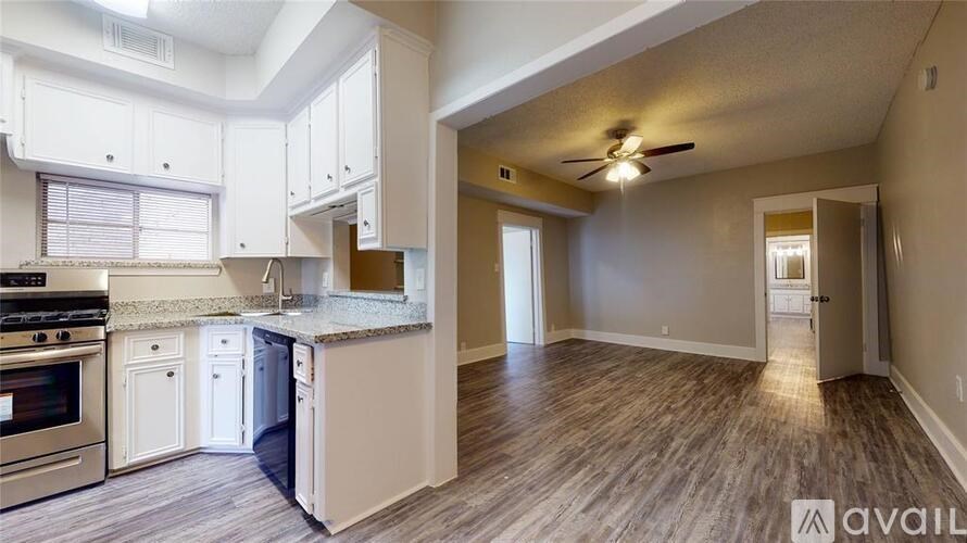 A kitchen with white cabinets and a wooden floor.