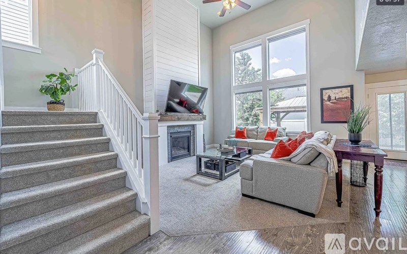 A living room with a grey couch, a fireplace, and a staircase.