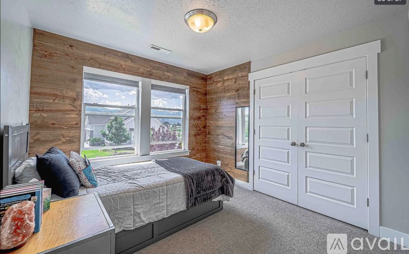A bedroom with a bed, dresser, and a window overlooking a green landscape.