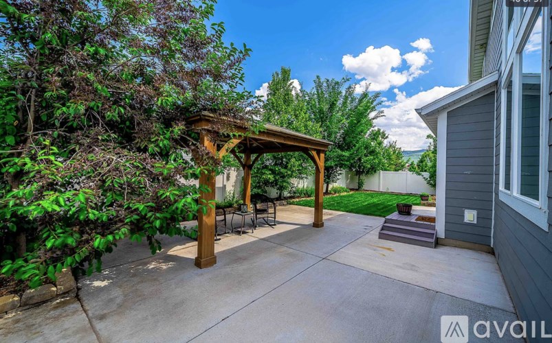 A patio with a wooden pergola and a cement floor.