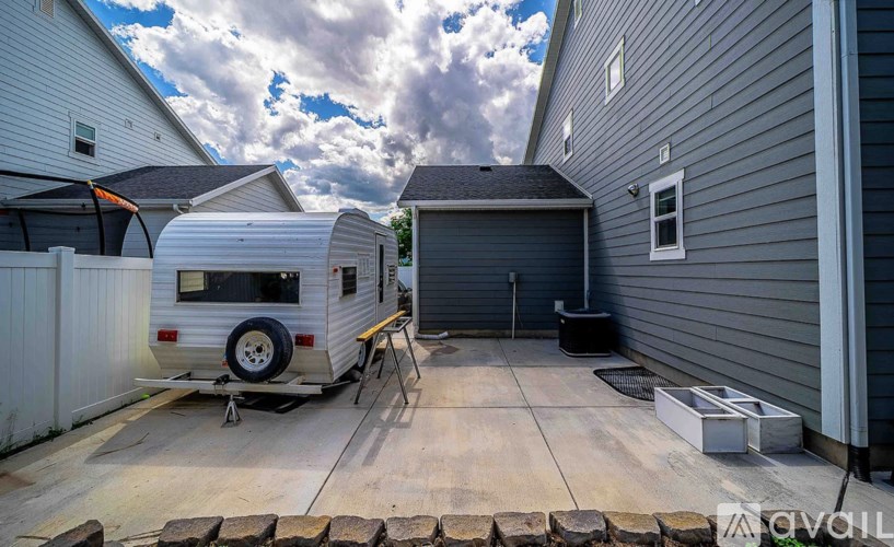 A white trailer is parked in a driveway next to a house.