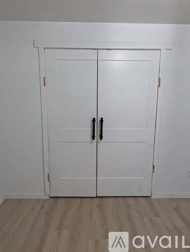 A white double door with black handles in a room.