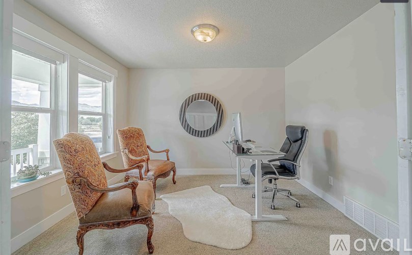 A room with a round mirror, a desk, and a chair.