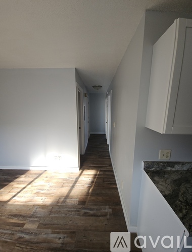 A room with wooden flooring and a black refrigerator.