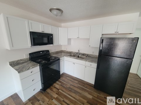 A kitchen with black appliances and white cabinets.
