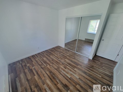 A room with wooden flooring and white walls.