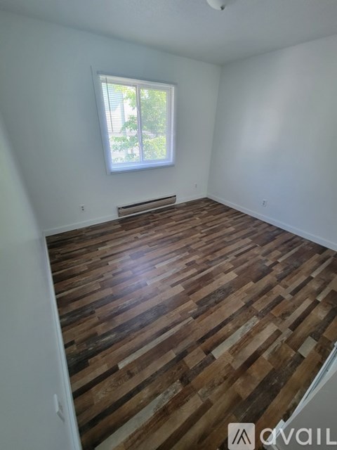 A room with wooden flooring and a window.