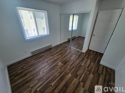A room with wooden flooring and a window with blinds.