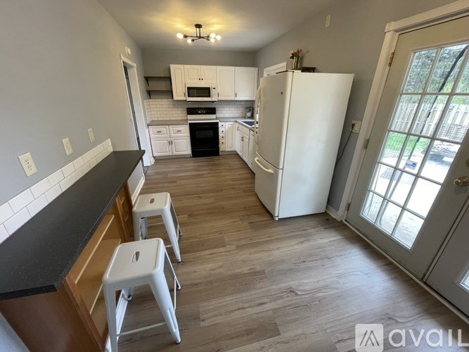 A kitchen with white appliances and wooden floors.