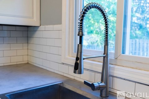 A kitchen sink with a chrome faucet and a coiled hose.