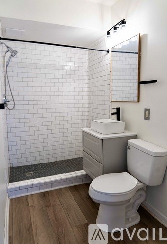 A white toilet sits next to a white sink in a bathroom with white tiles.