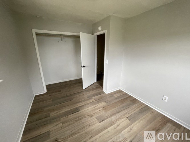 A room with wooden flooring and a door on the right side.
