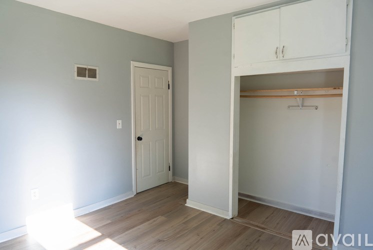 A room with a white door and a white cabinet with a shelf.