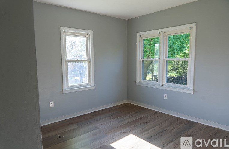 A room with two windows and wooden flooring.
