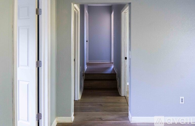 A hallway with a white door on the left and a white wall on the right.