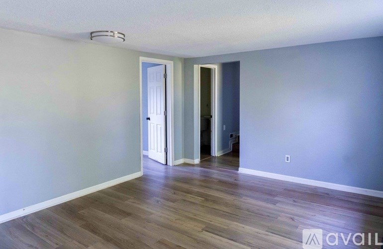 A room with wooden flooring and two doors.