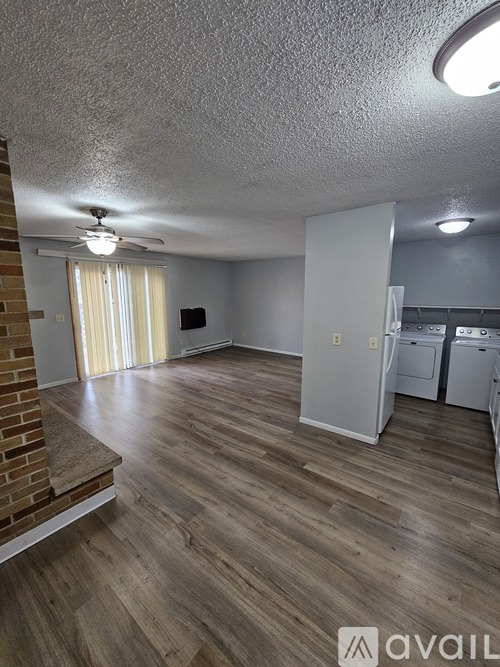 A room with wooden flooring and a brick wall on the left side.