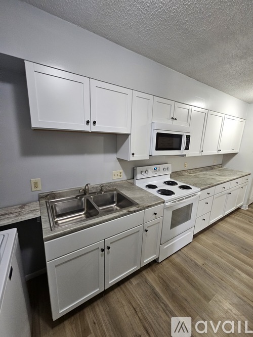 A kitchen with white cabinets and a wooden floor.