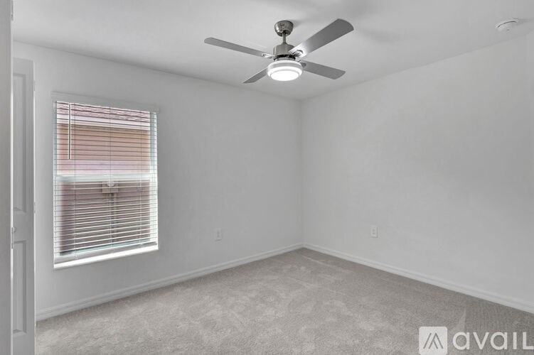 A room with a ceiling fan and a window with blinds.