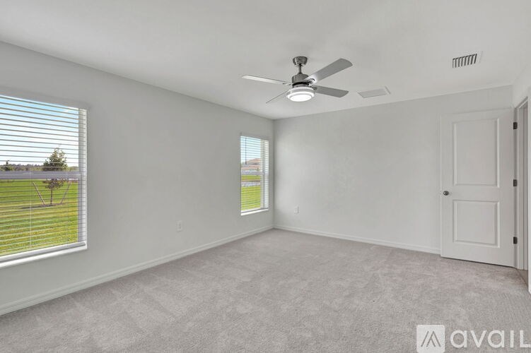 A room with a ceiling fan and two windows.