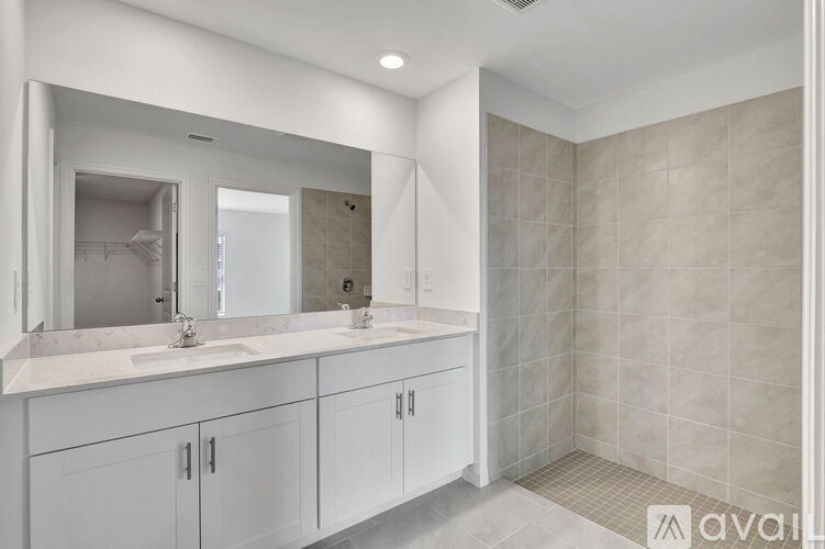 A bathroom with a large mirror, sink, and cabinets.
