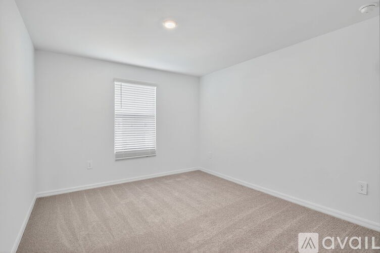 A grassy field with a tree in the middle and houses in the background.