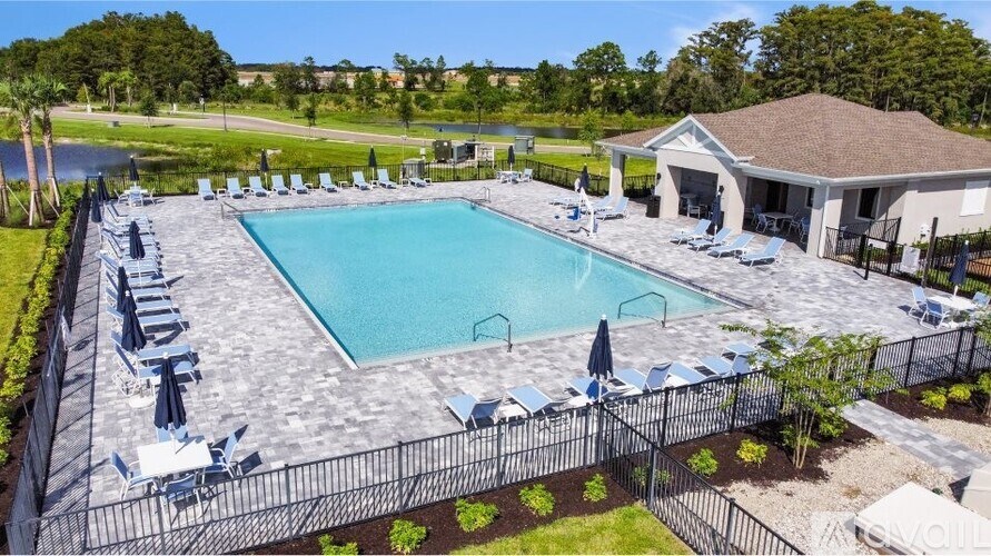 A large outdoor swimming pool surrounded by a black fence and lounge chairs.