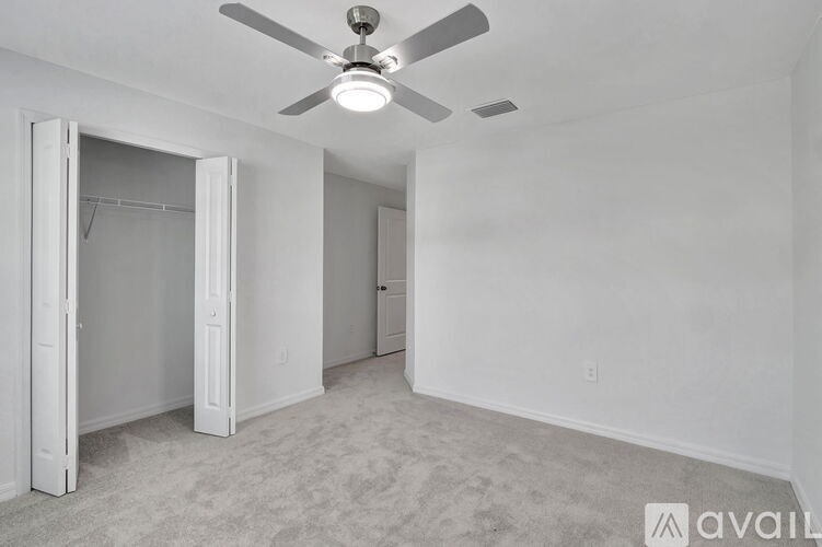 A room with a ceiling fan and carpeted floor.
