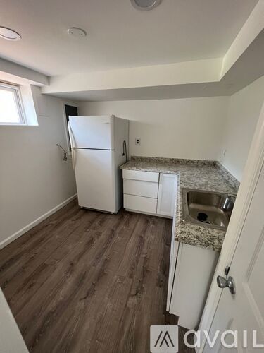 A kitchen with a white fridge and a sink with a granite countertop.