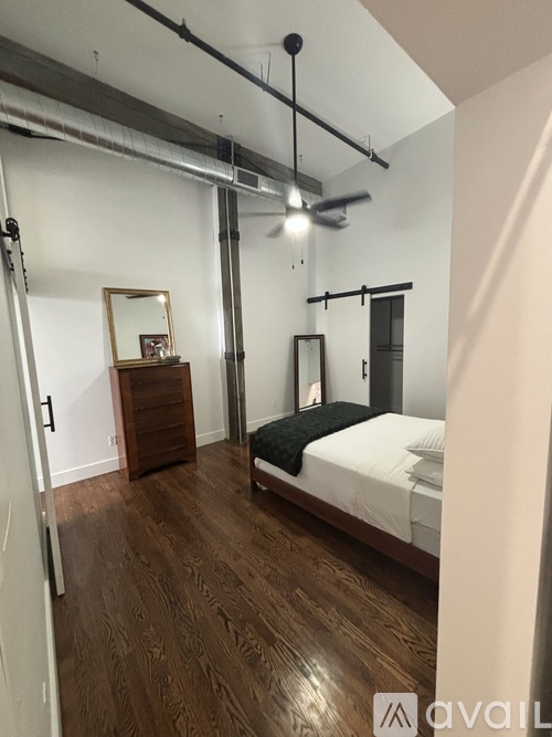 A bedroom with a bed, dresser, mirror, and a ceiling fan.