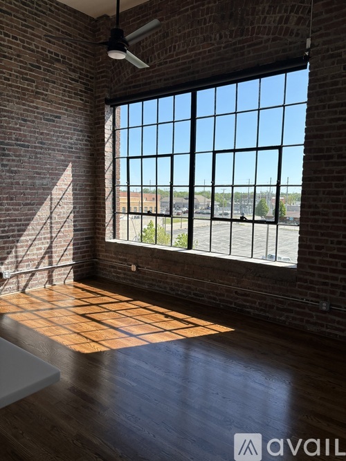A room with a brick wall and a large window overlooking a parking lot.