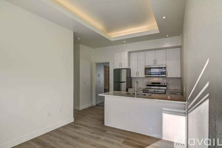 A modern kitchen with white cabinets and a wooden floor.