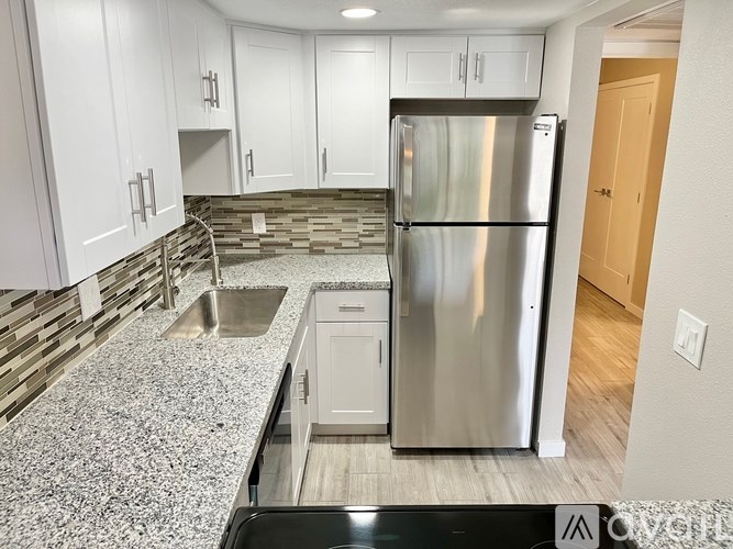 A kitchen with a stainless steel refrigerator and white cabinets.