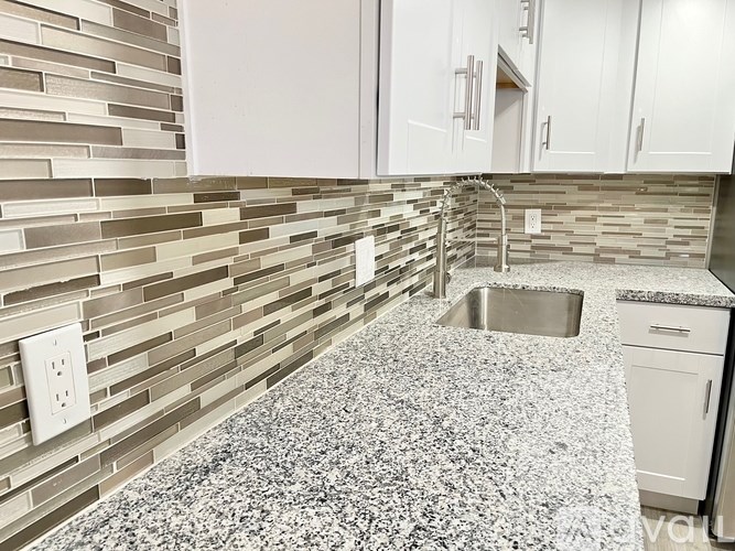 A kitchen with a granite countertop and white cabinets.