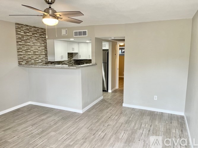 A room with a ceiling fan and a stone wall.