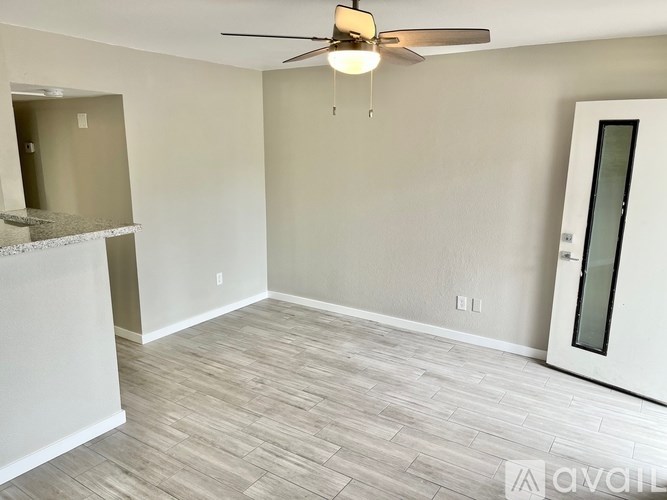 A room with a ceiling fan and light fixture, and a door with a glass panel.