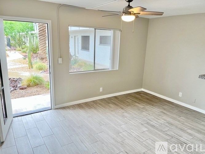 A room with a ceiling fan and a sliding glass door leading to a backyard.
