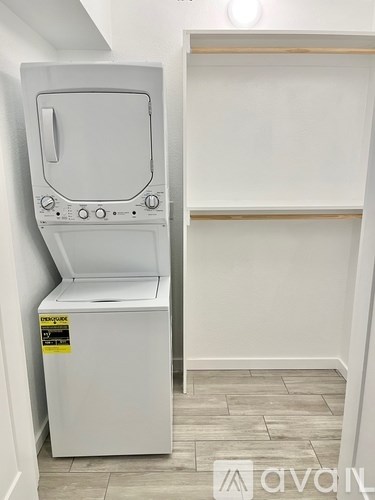 A white appliance with a sticker on it is in a room with a shelf.