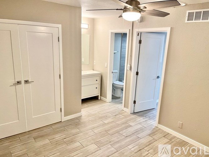 A room with a fan, a toilet, and a sink.