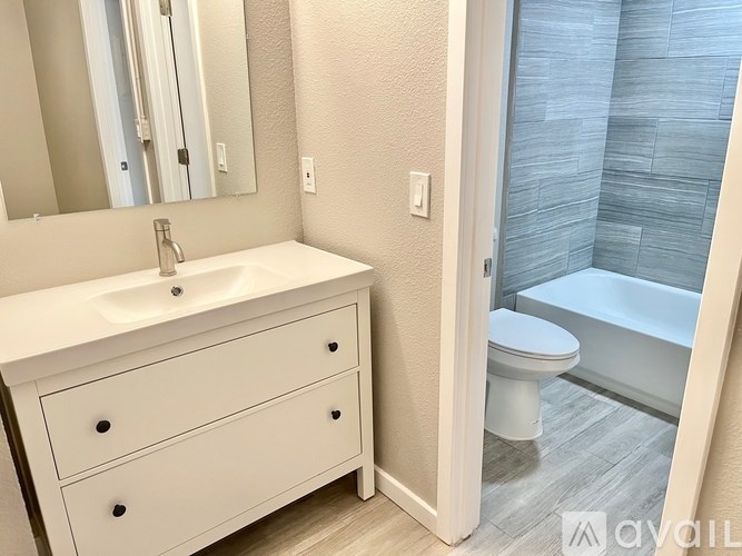 A white bathroom with a sink, mirror, and toilet.